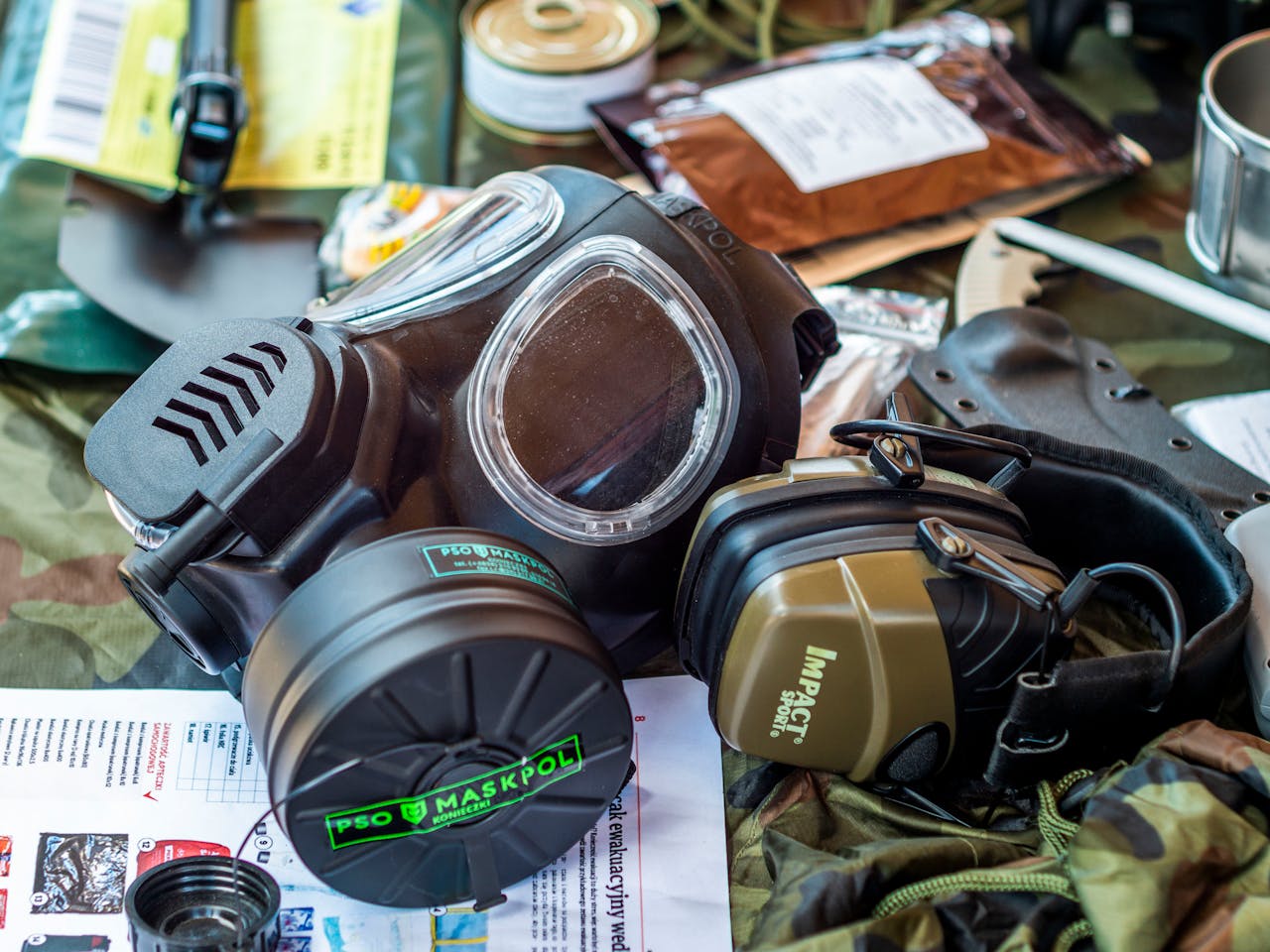 Services Survival gear including a gas mask and tactical headset on a camouflage background.